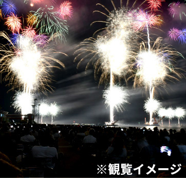観覧イメージ。多くの人がパイプ椅子に座り、正面に花火が上がっている。