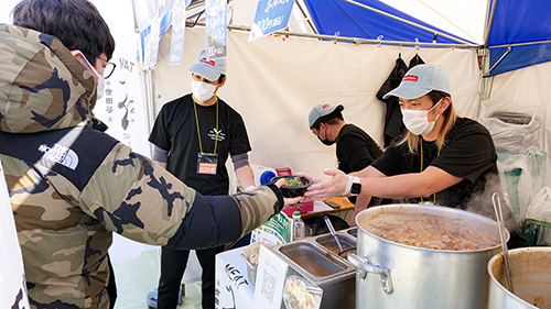 出店で煮物を受け渡しする店員と客